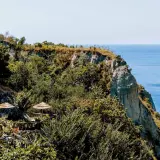 Terrazza panoramica con ombrelloni di paglia e vista sul mare a Nitrodi, Ischia.