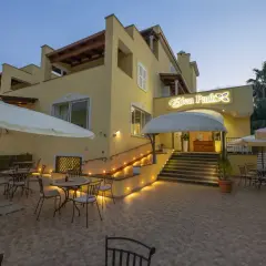 L'Eden Park a Ischia, con la sua facciata gialla illuminata, invita a rilassarsi nei suoi tavolini all'aperto sotto gli ombrelloni.