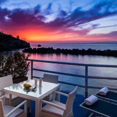 Terrazza con tavolo e sedie, lettini prendisole e un tramonto mozzafiato sul mare, un sogno in un blu resort Ischia.