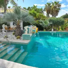 Piscina cristallina con cascata decorativa, lettini prendisole e area ristoro esterna. Un angolo di relax che ricorda le terme comunali di Ischia.