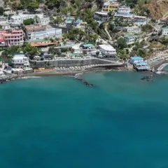 Vista aerea della spiaggia di Cava dei Tirreni, con case colorate arroccate sulla collina e il mare turchese.