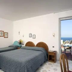 Camera con due letti singoli e un letto matrimoniale, con vista mare dal balcone. L'Hotel Gemma offre un soggiorno rilassante.