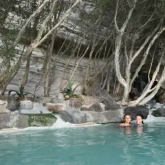 Due bambine si godono un bagno rilassante in una piscina naturale, circondata da rocce e vegetazione, un luogo perfetto per terme gratuite.