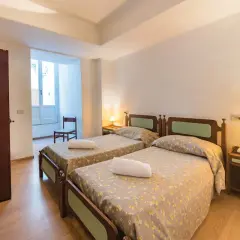 Camera doppia con letti singoli al Hotel Antonella Ischia, con biancheria a fiori e comodini in legno.
