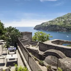 Terrazza con vista mare e un cameriere che serve ai tavoli. Un luogo incantevole, un albergo il monastero con un panorama mozzafiato.