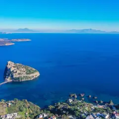 Aerial view of Castello Aragonese on a rocky island connected by a causeway to the coast of Ischia, Italy.