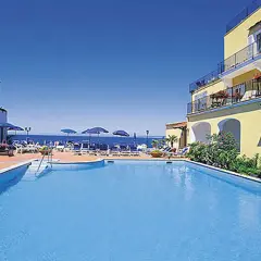 Piscina e mare azzurri al **hotel Parco Aurora Terme Ischia**. Lettini e ombrelloni invitano al relax.