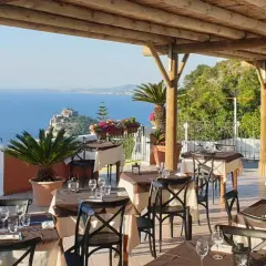 Terrazza con tavoli apparecchiati e vista mare a Ischia. Un vero nascondiglio dell'amore, perfetto per una cena romantica.