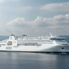 Traghetto bianco solca il mare, con le colline di Ischia vista da Napoli sullo sfondo.