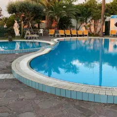 Piscine azzurre e lettini gialli al **hotel Monte Tabor**, un'oasi di relax tra palme e statue.