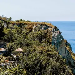 Terrazza panoramica con ombrelloni di paglia e vista sul mare a Nitrodi, Ischia.