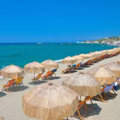 Spiaggia attrezzata con ombrelloni e lettini, mare azzurro e case in collina. Perfetto per chi cerca il **hotel San Valentino Ischia distanza dal mare** ideale.