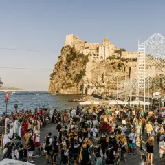Festa in costume sul lungomare, con il castello sullo sfondo. La spiaggia degli inglesi è animata da figuranti e spettatori.