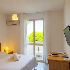 Camera accogliente al paradise relais villa janto, con letto comodo, TV e balcone con vista sul verde.