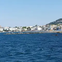 La costa di Ischia vista dal mare, con il castello Aragonese in lontananza. Immagina i traghetti Formia Ischia che ti portano qui.