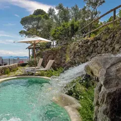 Piscina con cascata e vista mare, ideale per scoprire cosa curano le terme di Ischia. Relax e benessere assicurati.