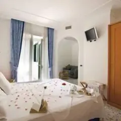 Camera accogliente con letto decorato con petali di rosa, un tavolino con colazione e un armadio in legno. Un'oasi di relax al hotel terme mediterraneo Ischia.