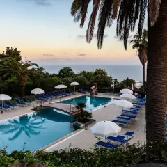Piscina con lettini e ombrelloni al tramonto, vista mare. Un'oasi di relax all'Hotel Calitto Ischia.