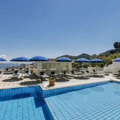 Piscina e lettini sotto ombrelloni blu al **hotel villa d'Orta Casamicciola**. Vista mare e collina.