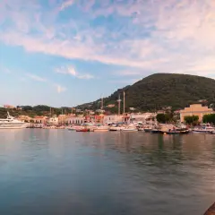 I **porti di Ischia** al tramonto, con barche ormeggiate e colline verdi sullo sfondo.