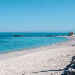 Spiaggia del Convento: sabbia chiara, mare azzurro cristallino, rocce e un faraglione solitario. Un angolo di paradiso.