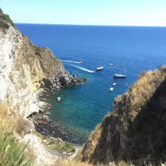 Baia di Panza, Ischia: scogliere a picco sul mare blu, barche a vela e un angolo di paradiso per nuotare.