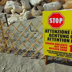 Spiaggia delle fumarole: segnale di pericolo indica sabbia bollente a 100°C, con una staccionata in bambù a delimitare l'area.