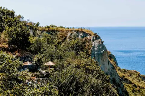 Terrazza panoramica con ombrelloni di paglia e vista sul mare a Nitrodi, Ischia.