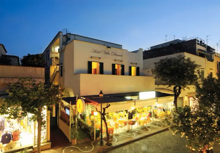 Hotel Villa Diana a Ischia, con un ristorante all'aperto illuminato e negozi.