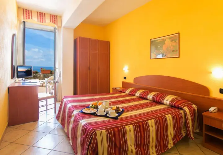 Camera accogliente con vista mare all'Hotel Parco dei Principi Ischia. Colazione servita sul letto, pronta per iniziare la giornata.