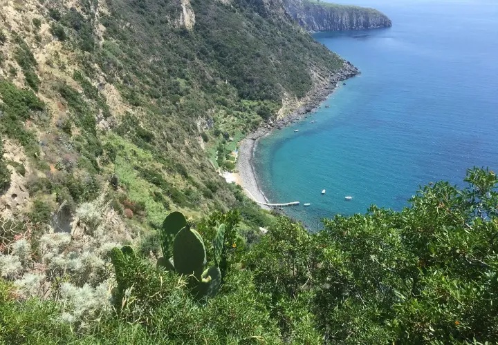 Vista mozzafiato su una baia con acque cristalline e vegetazione lussureggiante. La scarrupata a Ischia, un angolo di paradiso selvaggio.
