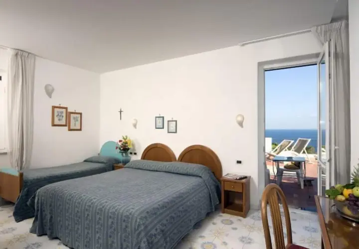 Camera con due letti singoli e un letto matrimoniale, con vista mare dal balcone. L'Hotel Gemma offre un soggiorno rilassante.