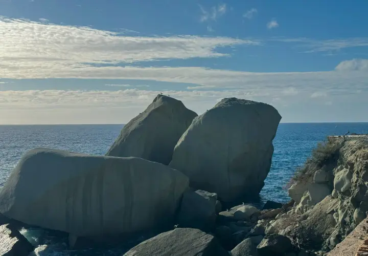 Scogli degli innamorati baciati dal sole, con il mare blu e nuvole bianche nel cielo.