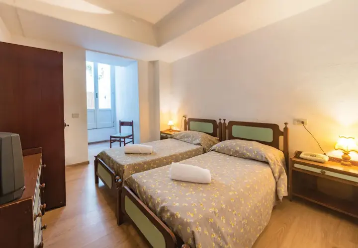 Camera doppia con letti singoli al Hotel Antonella Ischia, con biancheria a fiori e comodini in legno.