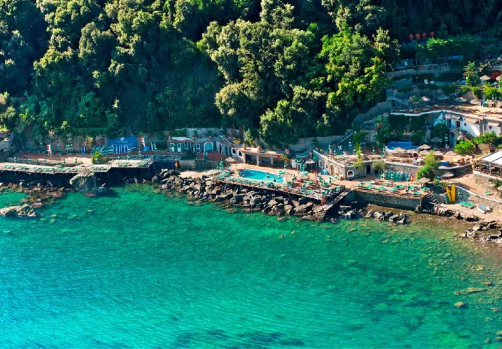 Un incantevole **bagnitiello a Ischia**, con acque cristalline, una piscina panoramica e una lussureggiante vegetazione che abbraccia la costa rocciosa.
