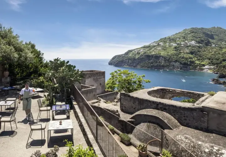 Terrazza con vista mare e un cameriere che serve ai tavoli. Un luogo incantevole, un albergo il monastero con un panorama mozzafiato.