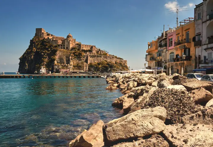 Castello Aragonese su uno scoglio, case colorate e mare cristallino. Chissà come si chiamano gli abitanti di Ischia, i veri protagonisti di questo scorcio.