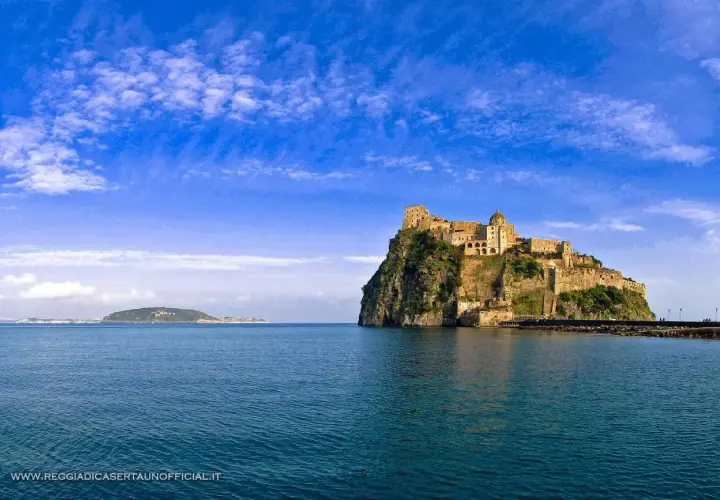 Il **palazzo reale** di Ischia, arroccato su uno scoglio, domina il mare blu sotto un cielo terso.