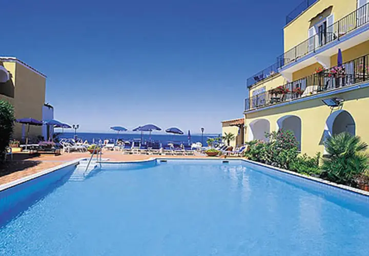 Piscina e mare azzurri al **hotel Parco Aurora Terme Ischia**. Lettini e ombrelloni invitano al relax.