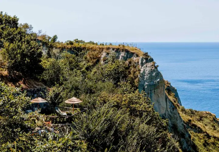 Terrazza panoramica con ombrelloni di paglia e vista sul mare a Nitrodi, Ischia.