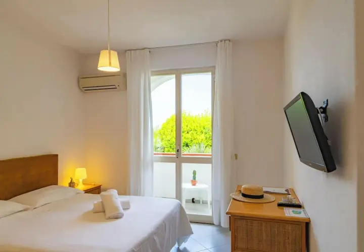 Camera accogliente al paradise relais villa janto, con letto comodo, TV e balcone con vista sul verde.
