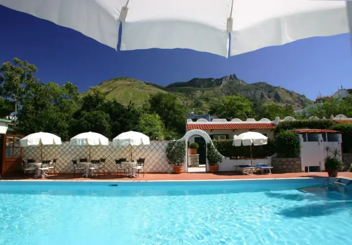 Piscina e tavoli all'aperto con vista sulle montagne, un angolo di relax all'hotel Lord Byron Forio.
