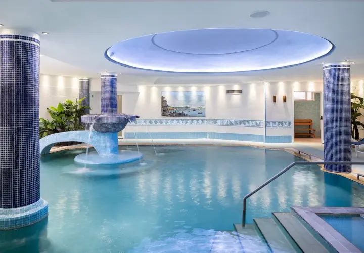 Piscina interna con cascata e piante, un'oasi di relax in uno spa a Ischia.