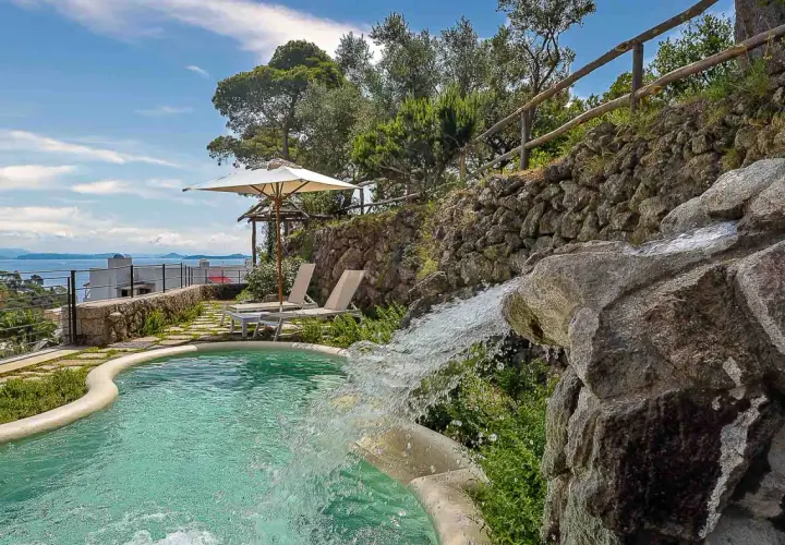 Piscina con cascata e vista mare, ideale per scoprire cosa curano le terme di Ischia. Relax e benessere assicurati.