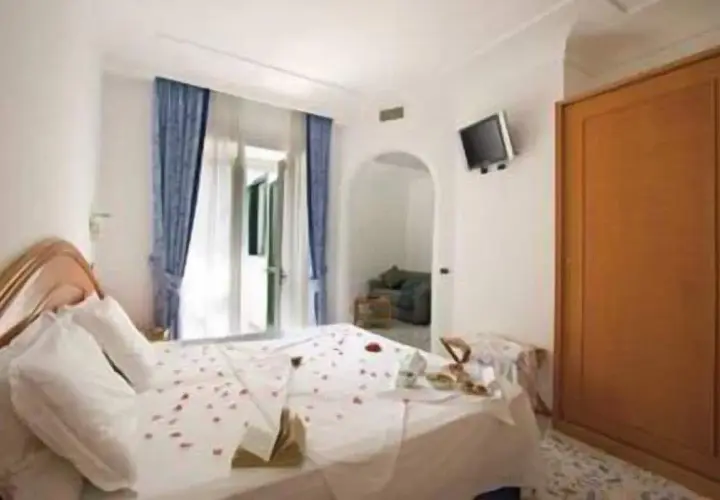 Camera accogliente con letto decorato con petali di rosa, un tavolino con colazione e un armadio in legno. Un'oasi di relax al hotel terme mediterraneo Ischia.