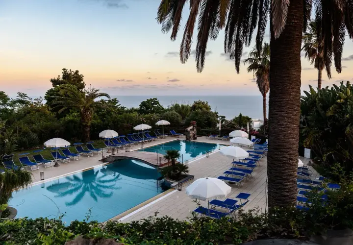 Piscina con lettini e ombrelloni al tramonto, vista mare. Un'oasi di relax all'Hotel Calitto Ischia.