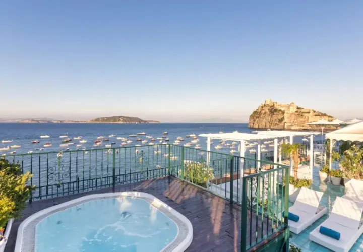 Terrazza con vasca idromassaggio e vista sul mare, barche e il Castello Aragonese. Un sogno al **Hotel Miramare e Castello Ischia**.
