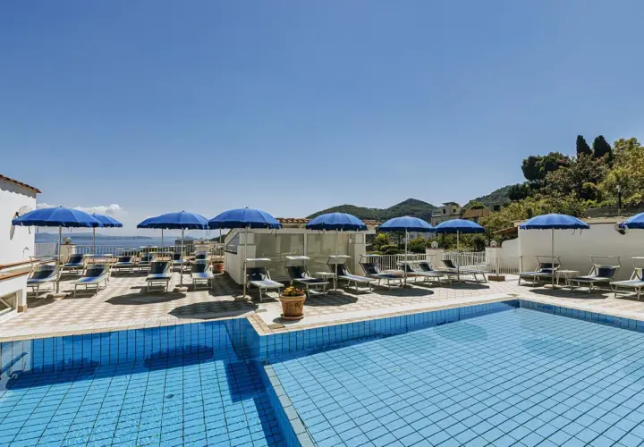 Piscina e lettini sotto ombrelloni blu al **hotel villa d'Orta Casamicciola**. Vista mare e collina.
