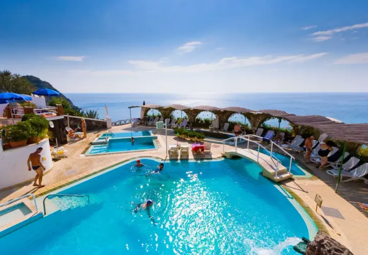 Relax in piscina con vista mare, un sogno a San Valentino Terme. Persone nuotano e si godono il sole.