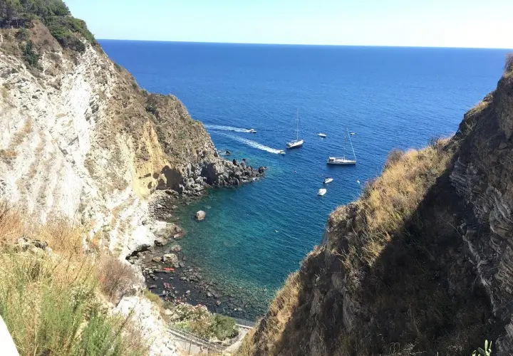Baia di Panza, Ischia: scogliere a picco sul mare blu, barche a vela e un angolo di paradiso per nuotare.